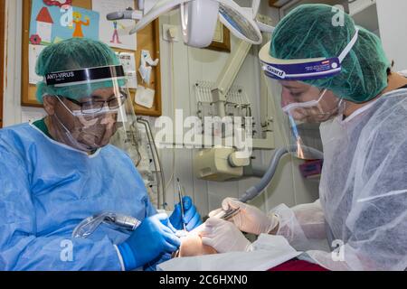 Gerusalemme, Israele - 14 giugno 2020: Un dentista e il suo assistente indossano un completo dispositivo protettivo antivirale durante un trattamento dentale. Foto Stock