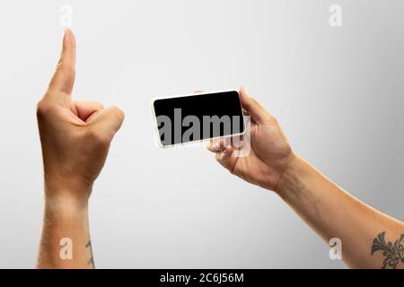 Momenti emozionanti. Primo piano mani maschili che tengono il telefono con schermo vuoto durante la visione online di partite popolari sport, campionati. CopySpace per l'annuncio. Concetto di dispositivi, gadget, tecnologie. Foto Stock