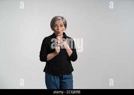 Donna che si innacia sorpresa in una camicia nera su sfondo bianco. Concetto di sconto di vendita. Annuncio vuoto con spazio di copia per il testo Foto Stock