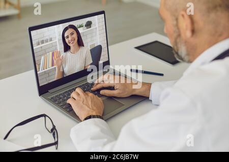 Medico e paziente online. Ragazza paziente dice consulti usando la webcam del laptop con il medico dell'uomo anziano alla clinica virtuale. Foto Stock