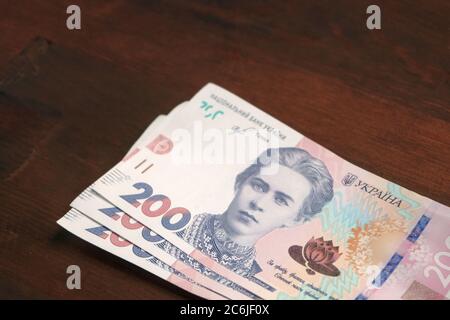 Nuovi soldi di carta ucraini. Duecento note di hryvnia su sfondo di legno marrone. Concetto di cassa. Primo piano Foto Stock