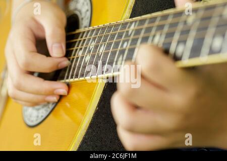 Un primo piano di un uomo sta suonando una chitarra acustica. Foto Stock