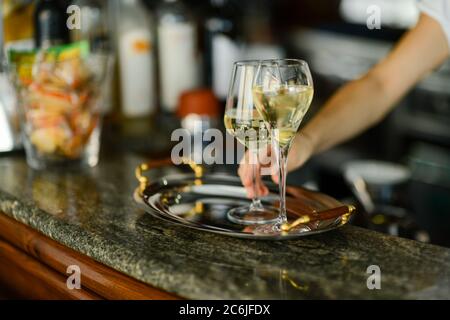 Due bicchieri di vino bianco freddo in un vassoio su un bancone bar con messa a fuoco selettiva e bokeh Foto Stock