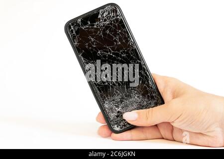 Smartphone nero moderno con schermo molto rotto in mano donne su sfondo bianco Foto Stock