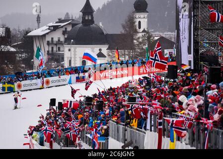 Johannes Hoesflot Klaebo termina il relè in primo luogo come tifosi onda la bandiera norvegese, 2019 World Nordic Ski Campionships, Seefeld, Austria. Foto Stock