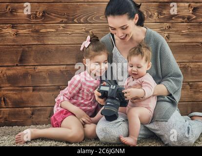 Fotografo in movimento. Giovane fotografo donna e bambine che si divertono alla sessione fotografica. Foto Stock