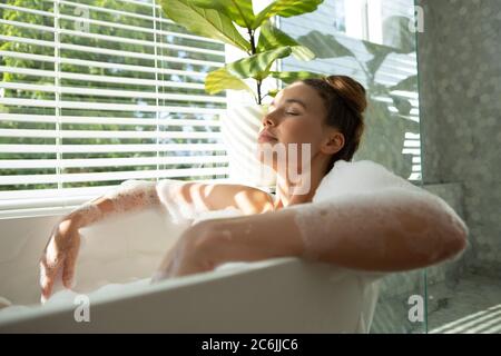 Donna rilassante in una vasca da bagno Foto Stock