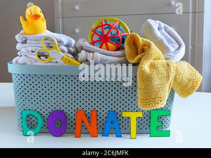 Confezione di plastica da donazione con giocattoli Unisex neutri per bambini sul tavolo in uno sfondo luminoso. Messa a fuoco selettiva. Foto Stock