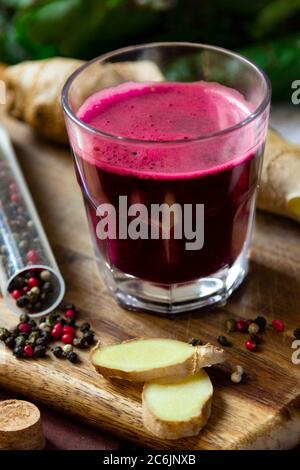 Succo di barbabietole fresco e speziato con zenzero su scrivania in legno, primo piano Foto Stock