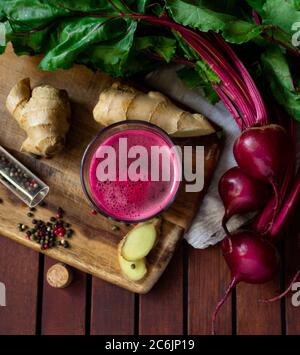 Succo di barbabietole fresco speziato con zenzero su tavolo di legno, piatto Foto Stock