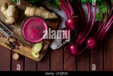 Succo di barbabietole fresco speziato con zenzero su tavolo di legno, piatto Foto Stock