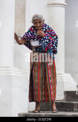 Guatemala, Dipartimento Solola, San Pedro la Laguna, una donna Maya anziana in abito tradizionale sui gradini della chiesa. Ha la sua tzute o panno di utilità avvolto intorno alle sue spalle. Foto Stock