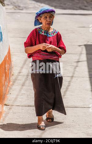 Una donna maya Cakchiquel più anziana in abito tradizionale cammina lungo la strada a Santa Cruz la Laguna, Guatemala. Foto Stock