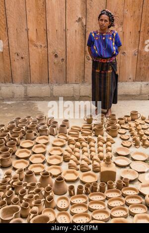 Guatemala, Solola, San Antonio Palopo, una donna maya Cakchiquel alla sua officina di ceramica nel vestito tradizionale compreso l'elaborato cinta o avvolgi capelli, blusa di huipil blu intrecciato, faja o cintura, e gonna di corte. Foto Stock