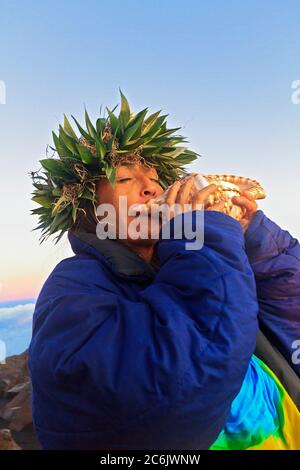 Barbara Bohonu, spirituale/culturale guaritore saluto alba con un canto e soffiando una conchiglia al Cratere Haleakala, Maui, Hawaii, USA. Foto Stock