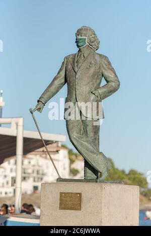 Cadaques, Spagna : 07 LUGLIO 2020 : Salvador Dali Statua nella spiaggia e le case del villaggio di Cadaques, Spagna in estate il 07 luglio 2020. Foto Stock