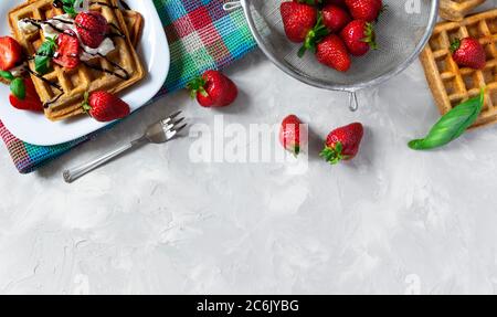 Waffle belgi quadrati fatti in casa con fragole, ricotta e cioccolato su piatto bianco. Vista dall'alto, spazio di copia Foto Stock