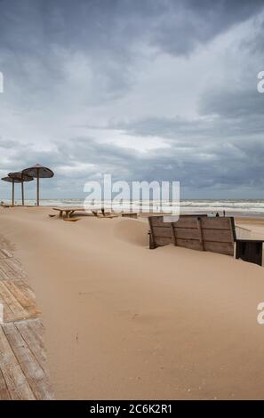 I tavoli coperti di sabbia sulla spiaggia di Egmont aan Zee, Paesi Bassi. La spiaggia senza turisti stranieri dopo la pandemia coronavirus. Foto Stock