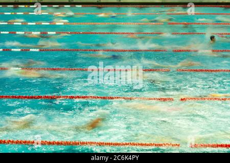 I nuotatori competitivi si riscaldano in piscina prima di correre. L'immagine è stata scattata con un'esposizione lunga per mostrare la sfocatura del movimento. Foto Stock