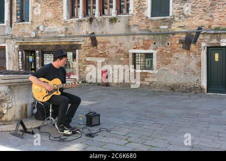 Venezia, Italia - 20 Aprile 2019: il giovane artista di strada a suonare la chitarra in un vecchio square Foto Stock