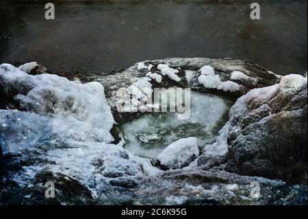 Vista ad alto angolo dei dettagli sulla spiaggia innevata. Rocce e acqua congelata. Foto orizzontale con livello di texture digitale. Foto Stock