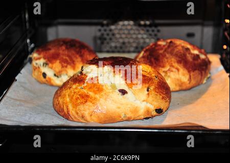 Tre torte norvegesi di Natale cracked nel forno. Pagnotte rotonde con uvetta e buccia candita. Shot orizzontale. Foto Stock