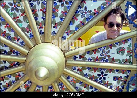 Ray Manzarek delle porte propone una foto con la ruota di un carro nel festival Hare Krishna mentre filma video per L.A. Donna a Venice Beach, CA circa 1984 Foto Stock