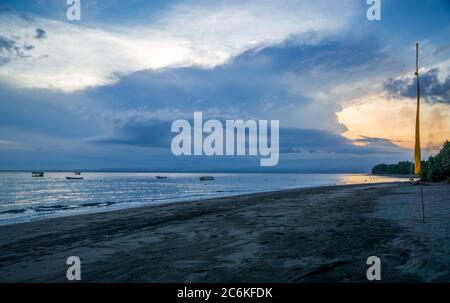 tramonto sul mare, spiaggia con bandiera pescatori barche sul mare Foto Stock