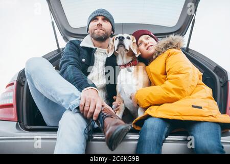 Padre e figlio con cane beagle che si siedono insieme nel bagagliaio dell'auto Foto Stock