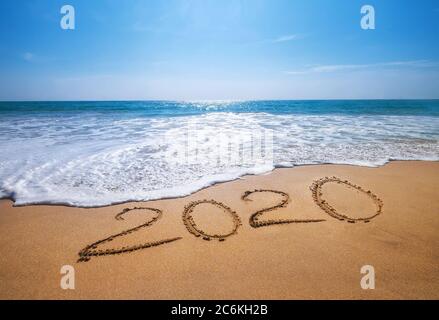 Felice anno nuovo 2020 sta venendo concetto di sabbia tropicale spiaggia caratteri oceano. Esotica celebrazione del nuovo anno Concept image. Foto Stock