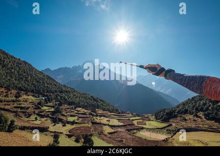Escursionista zaino in spalla uomo utilizzando i pali da trekking che si mostrano sulla montagna Thamserku 6608m durante l'alta altitudine acclimatazione passeggiata. Everest base Camp trekking ro Foto Stock