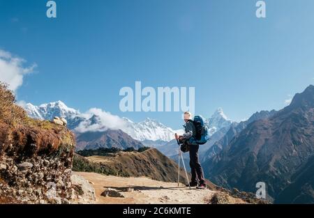 Giovane escursionista zaino in spalla con bastoni da trekking godendo la montagna di picco ama Dablam 6814m durante la camminata di acclimatazione ad alta quota. Base Cam Everest Foto Stock