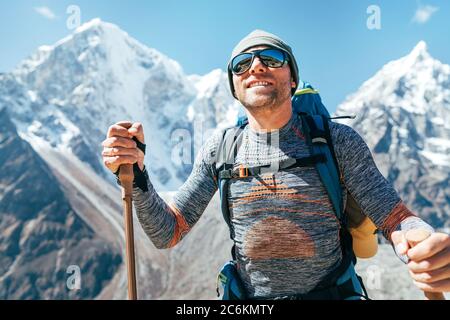 Ritratto di sorridente Hiker su Taboche 6495m e Cholatse 6440m cime sfondo con bastoni da trekking, occhiali da sole UV protezione. Lui che gode di montagna Foto Stock