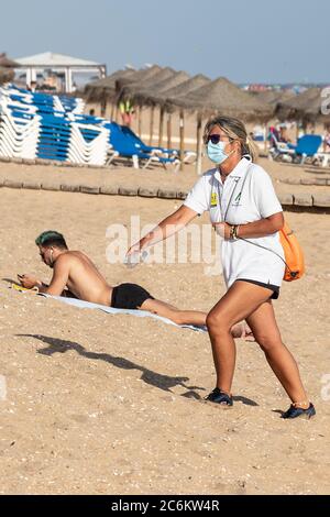Punta Umbria, Huelva, Spagna - 9 luglio 2020: Guardia di sicurezza della spiaggia di Junta de Andalucia sta controllando l'allontanamento sociale e l'uso di maschere protettive Foto Stock