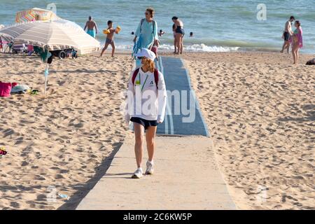 Punta Umbria, Huelva, Spagna - 9 luglio 2020: Guardia di sicurezza della spiaggia di Junta de Andalucia sta controllando l'allontanamento sociale e l'uso di maschere protettive Foto Stock
