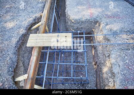 Piazzola piana per cantiere con trincea profonda di tre piedi e forme di calcestruzzo in posizione con filo di terra in rame per l'elettricità Foto Stock