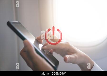 Donna mano uso smartphone in aereo con l'icona di disattivazione o disattivazione del segnale durante il volo.lavoro e concetto di viaggio. Foto Stock