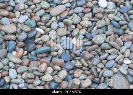 4 - centinaia di ciottoli color rosso e blu color mercoledì brillante creano uno sfondo semplice e rilassante. Pietre lisce trovate su una spiaggia. Foto Stock