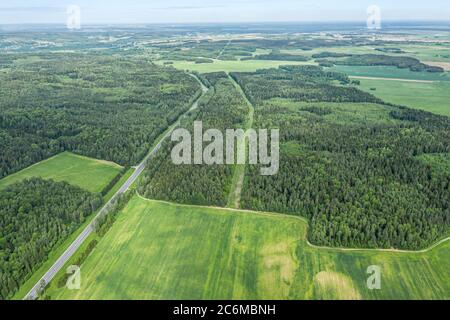 Vista aerea di una strada di campagna tra campi agricoli e foreste in Bielorussia. Paesaggio rurale estivo Foto Stock