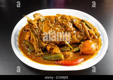 Serve di testa di pesce curry con okra e pomodoro, delicatezza popolare in Malesia Foto Stock