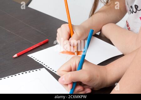 le mani dei bambini disegnano con matite colorate nei quaderni. Primo piano Foto Stock