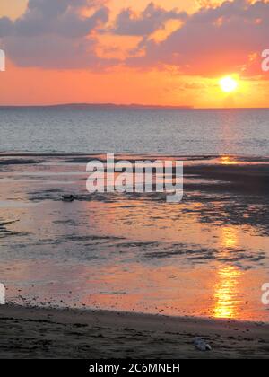 Alba sulla spiaggia di Vilanculos, Mozambico, con una vista frizzante del sistema di isole barriera di Bazaruto, appena visibile all'orizzonte Foto Stock