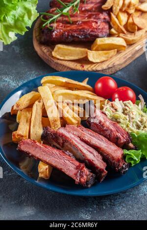 Costolette di maiale speziate alla griglia servite con patatine fritte e salsa barbecue Foto Stock