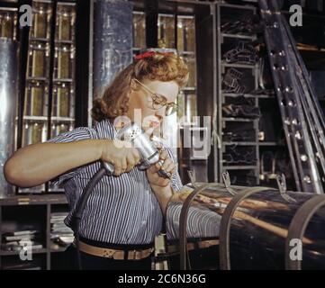 Il funzionamento di un trapano a mano presso la North American Aviation, Inc., [a] donna sta lavorando in superficie di controllo reparto assemblaggio di una sezione del bordo di attacco per il empennage orizzontale di un piano, Inglewood, Calif. - Ottobre 1942 Foto Stock