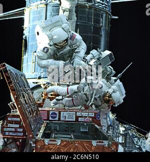 (13 febbraio 1997) ---- gli attrezzi in su con gli attrezzi per la prima attività extravehicular (EVA-1) per servire il telescopio spaziale Hubble (HST, background) sono astronauti Steven L. Smith (sinistra) e contrassegno C. Lee. Erano tra quattro membri dell'equipaggio STS-82 che devono condividere diverse sessioni di lavoro a piedi nello spazio a due membri alternate durante il volo. La fotografia è stata realizzata dall'interno della cabina di Discovery con una fotocamera da 70 mm. Foto Stock