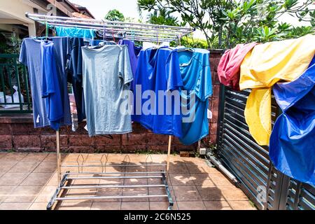 Tessuto di lavanderia che viene asciugato sotto il sole caldo luminoso in composto domestico dopo il lavaggio in Malesia Foto Stock