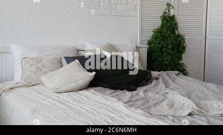 Letto non fatto in camera moderna. Da sopra calda coperta e morbidi cuscini collocati su comodi letti non fatti in elegante camera da letto contemporanea Foto Stock