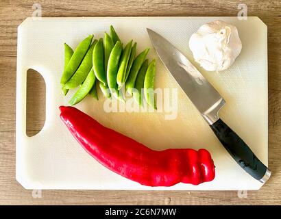 Deliziosi peperoni a punta e piselli a bottoncino dolci freschi Ramiro sul tagliere ingredienti per un pasto gustoso Foto Stock