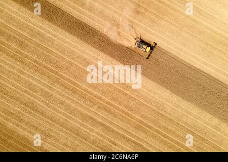 vista aerea di una mietitrebbia moderna in azione che termina la raccolta di un campo di grano Foto Stock