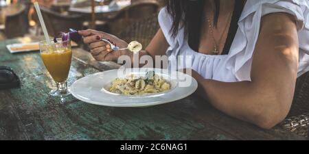 Spaghetti appetitosi sul piatto e succo sul tavolo. Da sopra gustosi tagliatelle fresche su piatto bianco e succo d'arancia in vetro Foto Stock